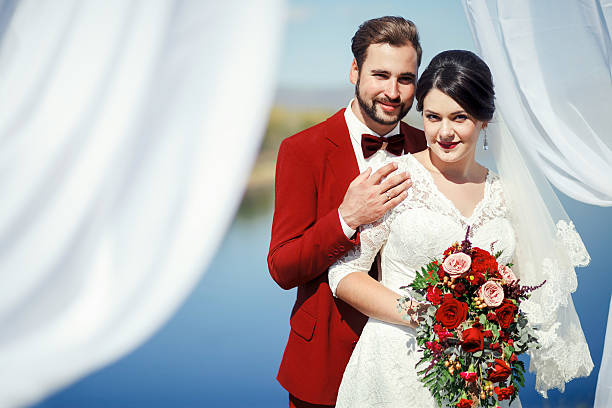 Newlyweds outdoor, groom in red suit stock photo