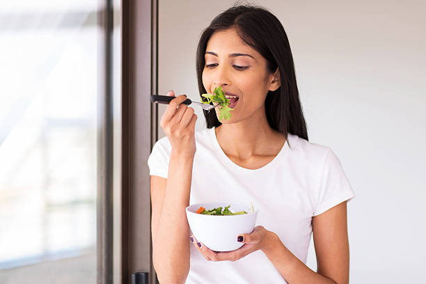 indian woman eating green salad stock photo