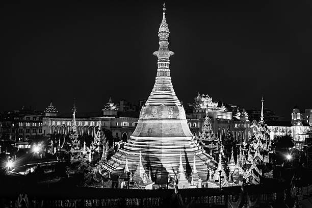 Aerial view of the famous and beautiful illuminated golden Sule Pagoda within a downtown road circle in the city center of Yangon - Rangoon at Night. Illuminated and decorated Yangon City Hall in the background. Yangon (Rangoon), Myanmar . Burma, South-East Asia. Edited Black and White.