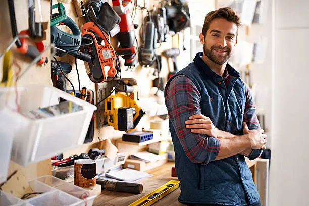 Portrait of a handsome young handyman standing in front of his work tools