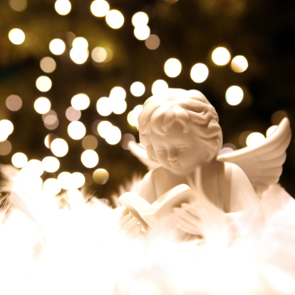 White angel figurine with Christmas lights in the background