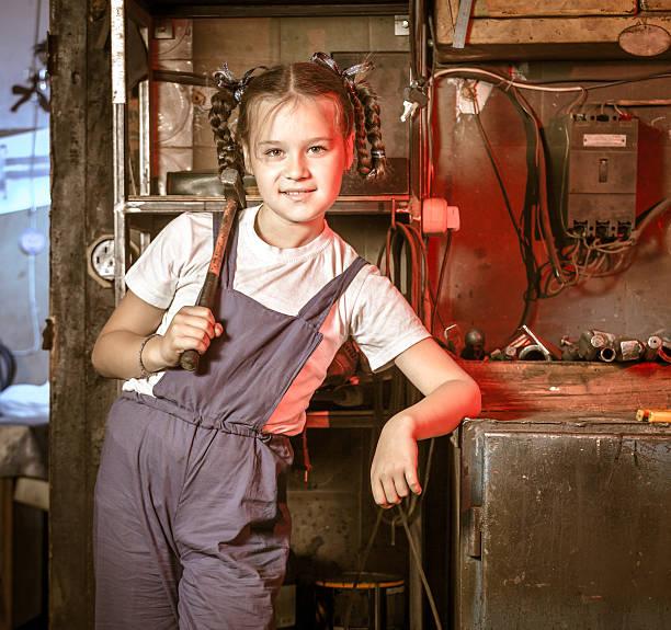 Portrait of working girl Beautiful girl mechanic with hammer on her shoulder standing at repair shop girl with a hammer stock pictures, royalty-free photos & images