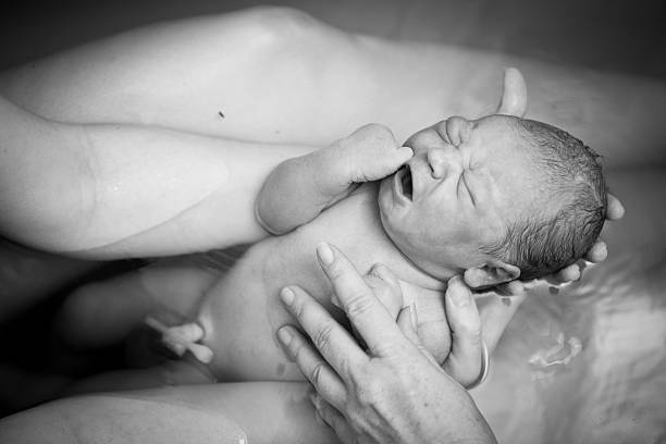 Mother Holding Newborn After Home Water Birth Black and white image of a young mother holding her newborn son after giving birth at home. home birth photos stock pictures, royalty-free photos & images