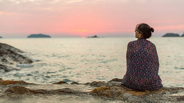 istock Woman wrapped in plaid sits lonely on the coast. 512697266