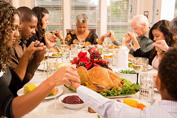 natal: família comendo férias prays antes do jantar. - family thanksgiving dinner praying - fotografias e filmes do acervo