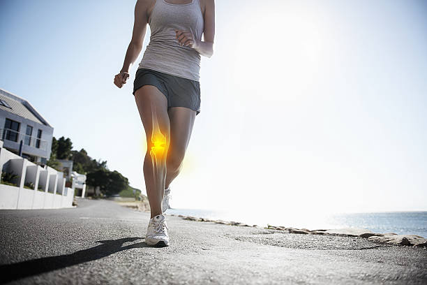 Running through the pain A cropped view of a female jogger on the road experiencing joint inflammation human knee stock pictures, royalty-free photos & images