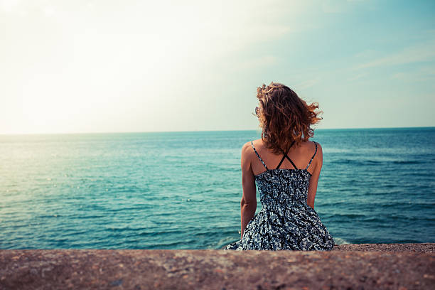 istock Young woman sitting by the ocean 512698369