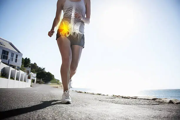 A cropped view of a female jogger on the road experiencing joint inflammation