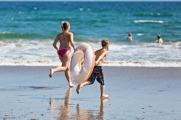 два дети, бег на океан - water sport family inner tube sport стоковые фото и изображения