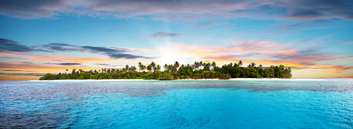 Beautiful nonsettled tropical island with perfect sunset sky and azure water with corals