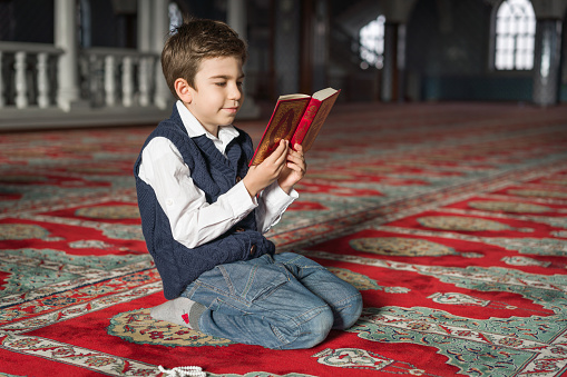 Kid reading The Holy Koran,mosque
