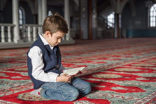 Kid reading The Holy Koran,mosque
