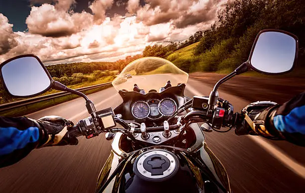 Biker driving a motorcycle rides along the asphalt road. First-person view.