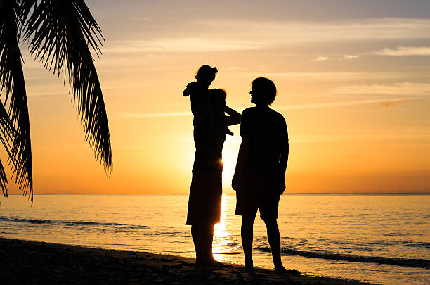 istock happy couple with little child at sunset beach 512704730