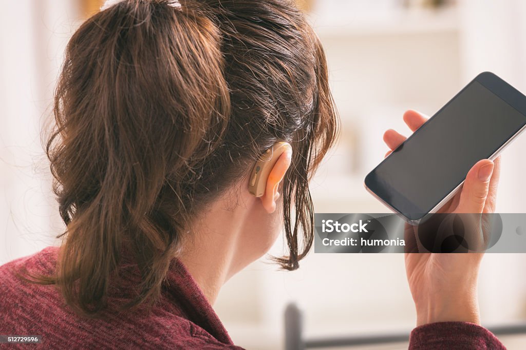 Sordos mujer usando teléfono inteligente - Foto de stock de Aparato auditivo libre de derechos
