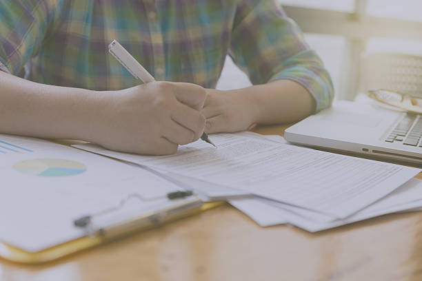 istock woman hand, pen, glasses, business document, laptop computer not 512733260