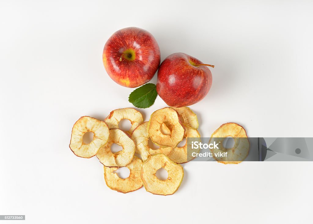 two whole apples and dried apple rings fresh red apples and dried apple rings on white background Apple Chips Stock Photo