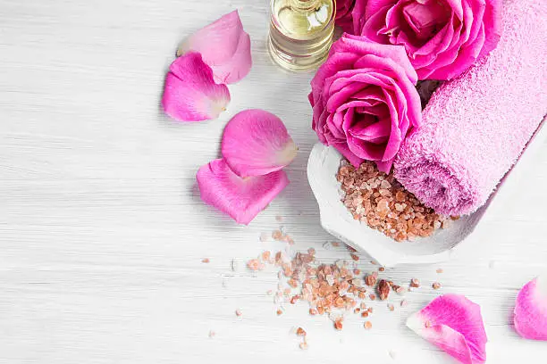 Spa setting with rose pink flowers and petals,bath salt and body-oil