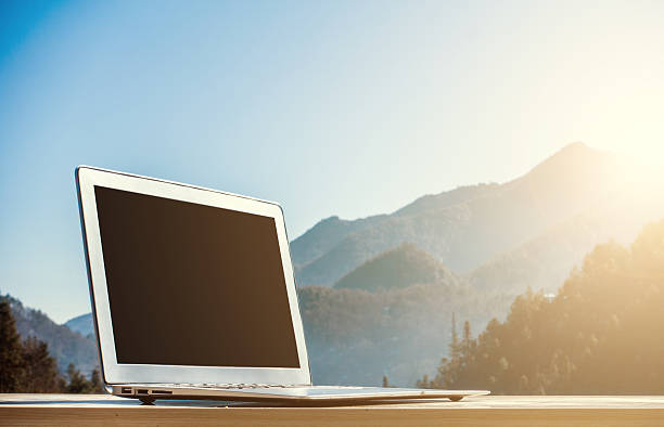 istock Laptop on wooden table with mountain background 512740892