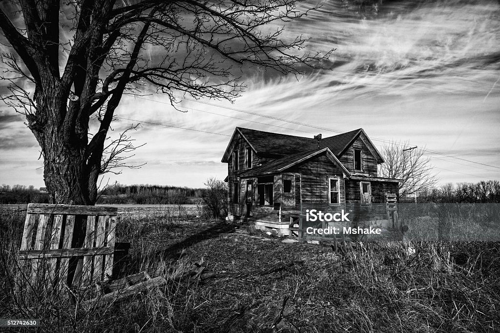 Creepy Old House Black and white photo of an old scary abandoned farm house that is deteriorating with time and neglect. Abandoned Stock Photo