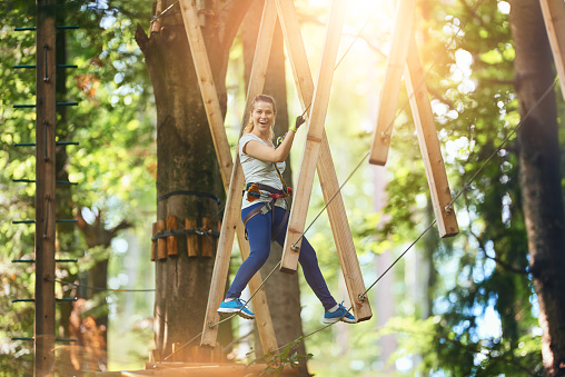photo of happy young woman in adventure park looking at camera and enjoying her sport adventures.