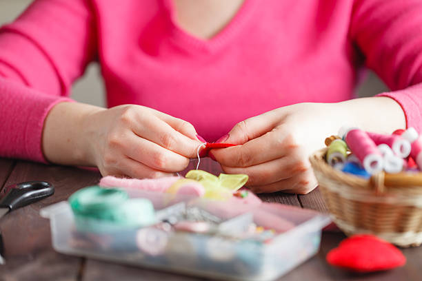 istock Woman sews red heart shaped toy by needle 512745512