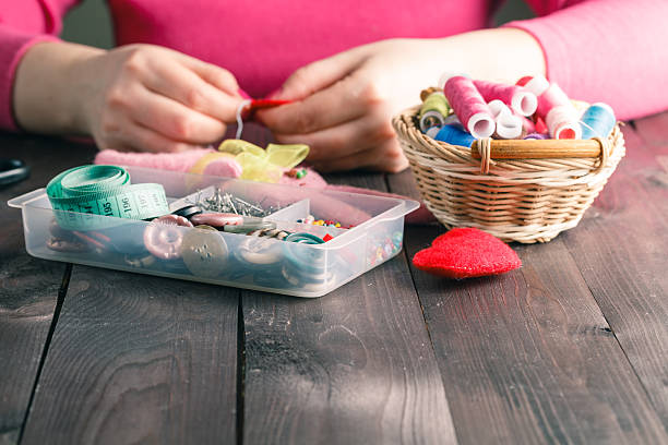 istock Woman sews red heart shaped toy by needle 512745554
