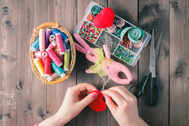 istock Woman sews red heart shaped toy by needle 512745636