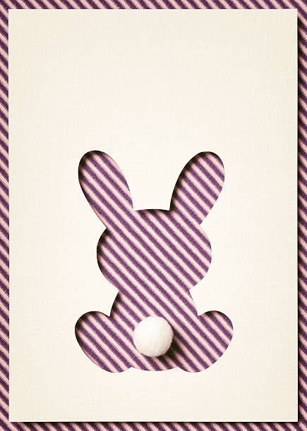 Photography of a cut out easter bunny on purple striped fabric.