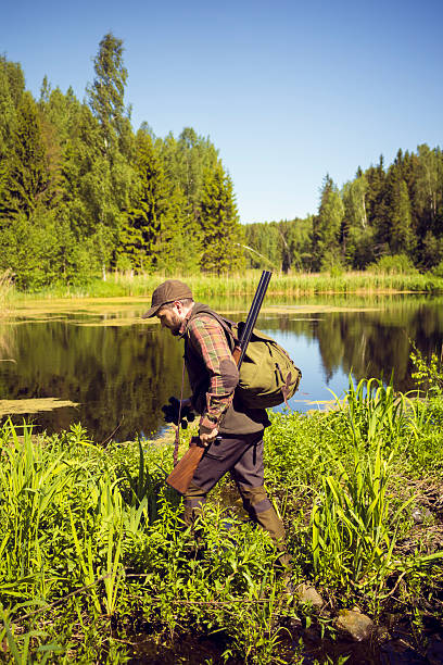 istock Mid Aged Man Walking With A Shortgun In A Swamp 512748362