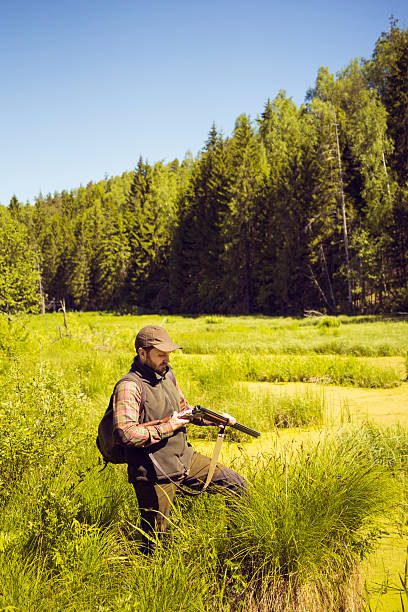 istock Man Charging His Shotgun While Standing In An Open Swamp 512749308