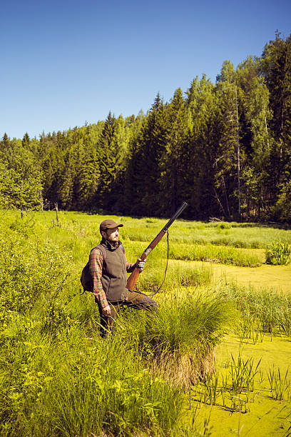 istock Man With A Shotgun Standing In An Open Swamp Scenery 512749482