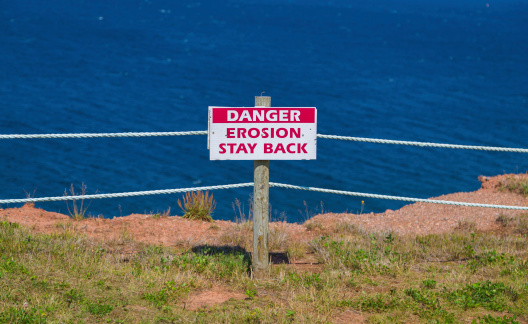 A sign warning people of Erosion on a cliff