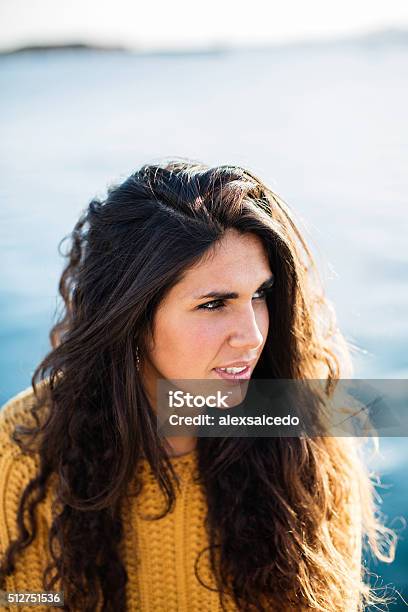 Portrait Of Young Woman Looking Away While Sitting On Pier Stock Photo - Download Image Now