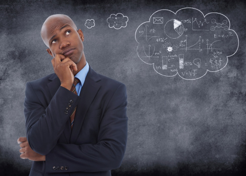 Conceptual shot of a businessman with a though bubble drawn on chalk behind hime