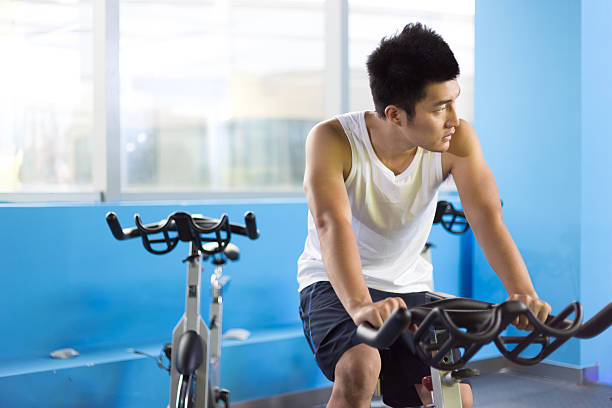 Young Caucasian man pushing himself to new limits on his state-of-the-art exercise bike, using the latest in fitness technology to achieve his health and fitness goals in the gym.