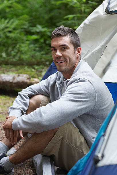 istock Portrait Of Smiling Man Sitting By Tent 512798539
