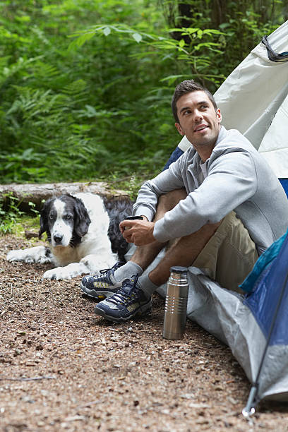 istock Man With Dog Sitting By Tent 512798541