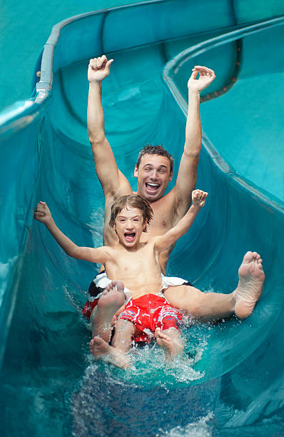 istock Father And Son With Arms Outstretched On Water Slide 512798551