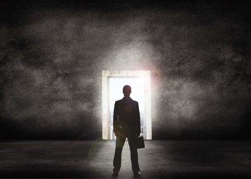 Conceptual shot of a businessman looking towards a bright doorway