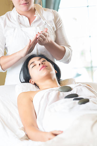 woman リラックス効果のあるコールドストーンセラピーでのスパマッサージ - massage therapist stone spa treatment working ストックフォトと画像
