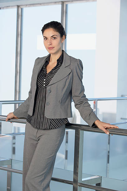 Portrait of beautiful businesswoman leaning on railing in office