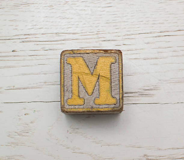 istock Wooden Block on whitewashed wood YellowLetter M 512800535