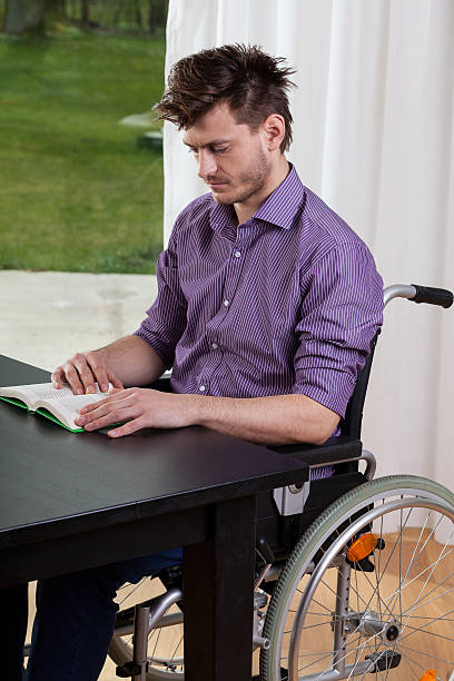 istock Man on wheelchair reading a book 512801459