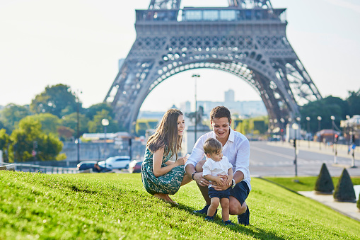 Happy family of three near the Eiffel tower and enjoying their vacation in Paris, France