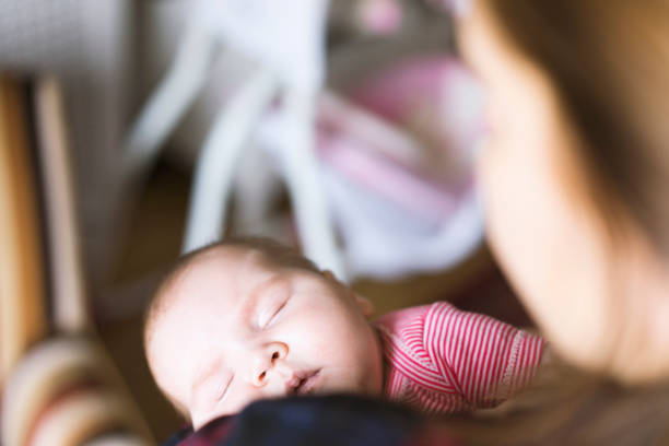 istock Newborn baby sleeping in her mother's arms 512814698