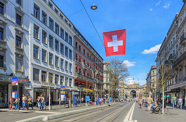 Bahnhofstrasse street in Zurich Zurich, Switzerland - 12 April, 2015: pedestrians on the Bahnhofstrasse street with the Zurich main railway station building in the background. Bahnhofstrasse is Zurich's main downtown street and one of the world's most expensive and exclusive shopping avenues. zurich train station stock pictures, royalty-free photos & images