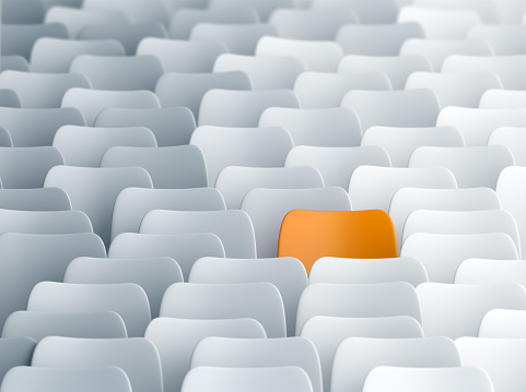 Yellow chair in a lecture hall full of white ones. Individuality, discrimination and contrasts concept