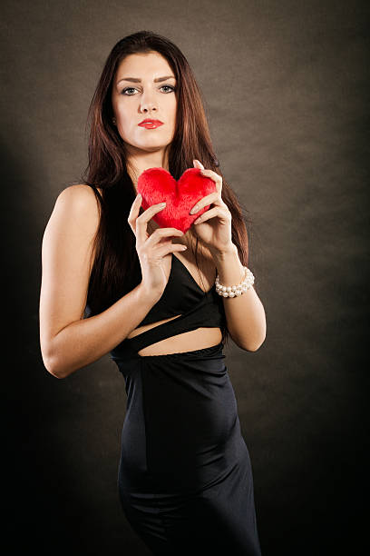 istock Beautiful woman holds red heart on black 512822438