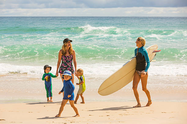 mãe e filhos na praia com surfista feminina - cabarita beach imagens e fotografias de stock